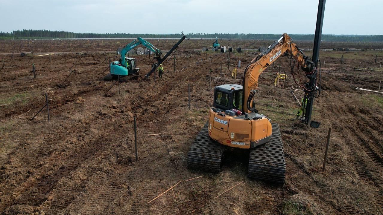 GPS-guided helical pile drill rig mounted on a peat-track excavator on a Nordic solar site