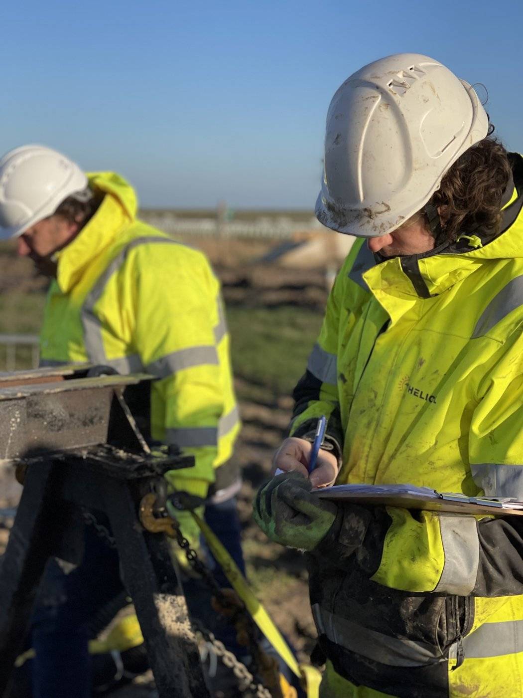 Helicasol engineer recording torque-verified pile data on site for re-engineering